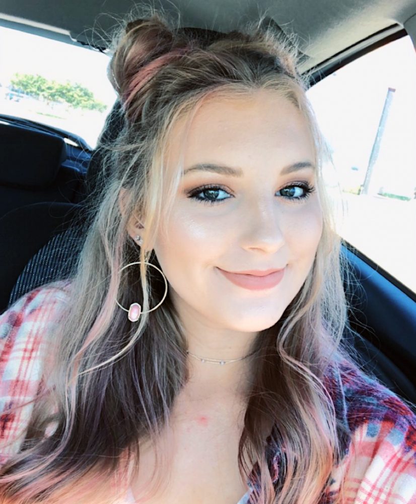Een high school studente met lang, golvend blond haar en een roze geruit overhemd lacht naar de camera terwijl ze in de auto zit. Op sociale media vertelde ze dat ze op school met de paddle op haar billen had gekregen omdat ze de motor van de auto te lang had laten doordraaien.