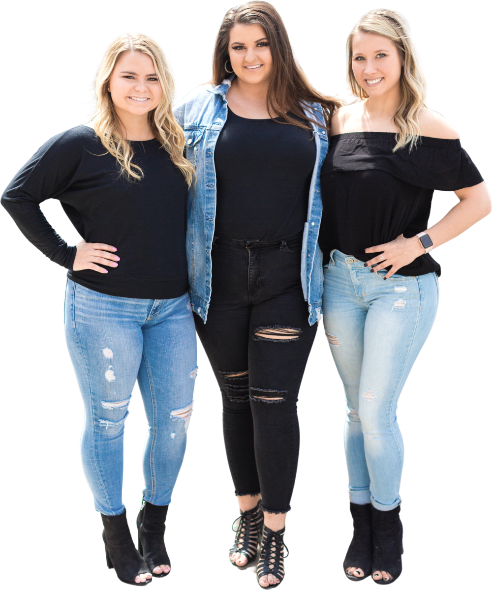 Drie vrouwen staan dicht bij elkaar en lachen naar de camera. Ze zijn allemaal casual gekleed, met jeans en zwarte tops.