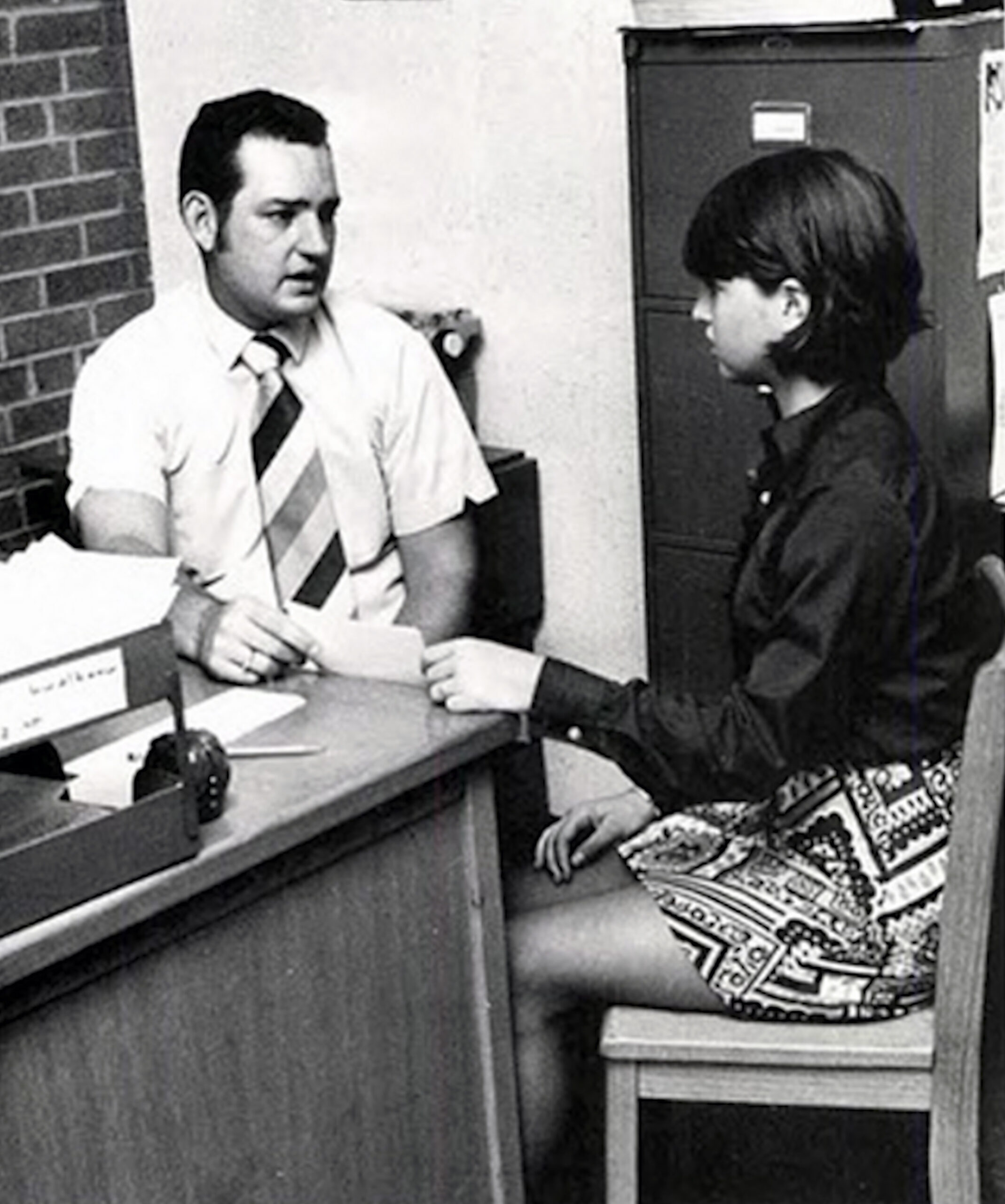 Een schooldirecteur en een High School studente zitten tegenover elkaar aan een bureau op een kantoor, verwikkeld in een gesprek. De studente gaat de volgende ochtend voor straf op haar billen krijgen. De man geeft een brief aan de studente dat door haar ouders ondertekend moet worden.