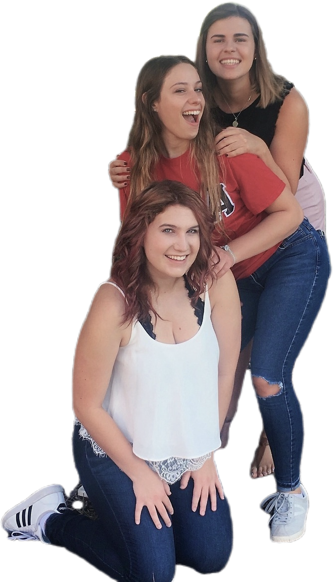 Drie jonge vrouwen poseren samen, glimlachend. Eén zit vooraan geknield, gekleed in een wit topje en een spijkerbroek. De twee achter haar staan, de een in een witte tanktop en spijkerbroek, de ander in een rood shirt en spijkerbroek.
