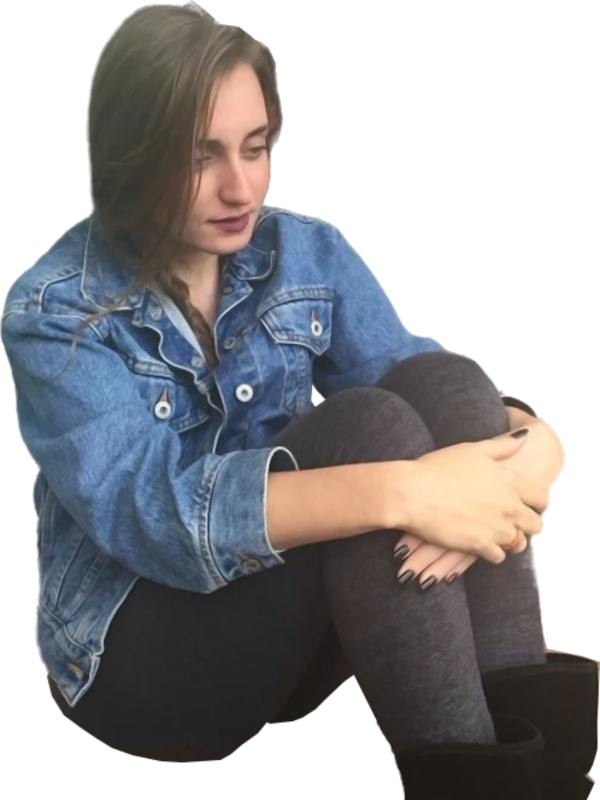 Een studente in een spijkerjasje en een donkere legging zit terwijl ze naar beneden kijkt.