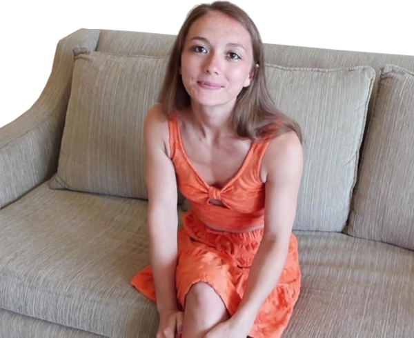 Een vrouw in een oranje jurk zit op een beige bank, kijkt met een lichte glimlach naar de camera en vangt een moment van aansluiting vinden temidden van eenzaamheid.