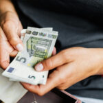 Twee handen houden een paar 5-Euro biljetten beet.