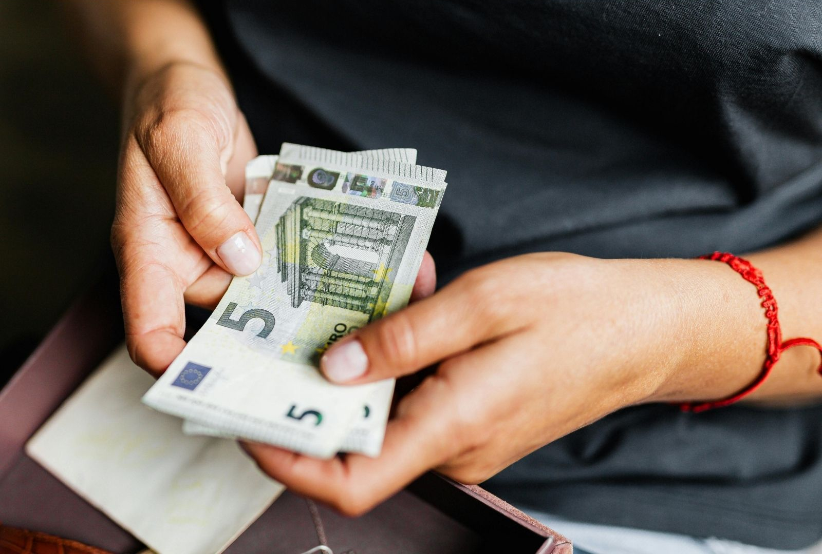 Twee handen houden een paar 5-Euro biljetten beet.